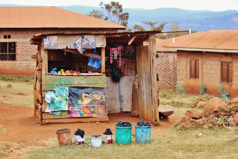 Fruit stall of wood and corrugated iron in Karatu, next to brick houses with red roofs on red earth