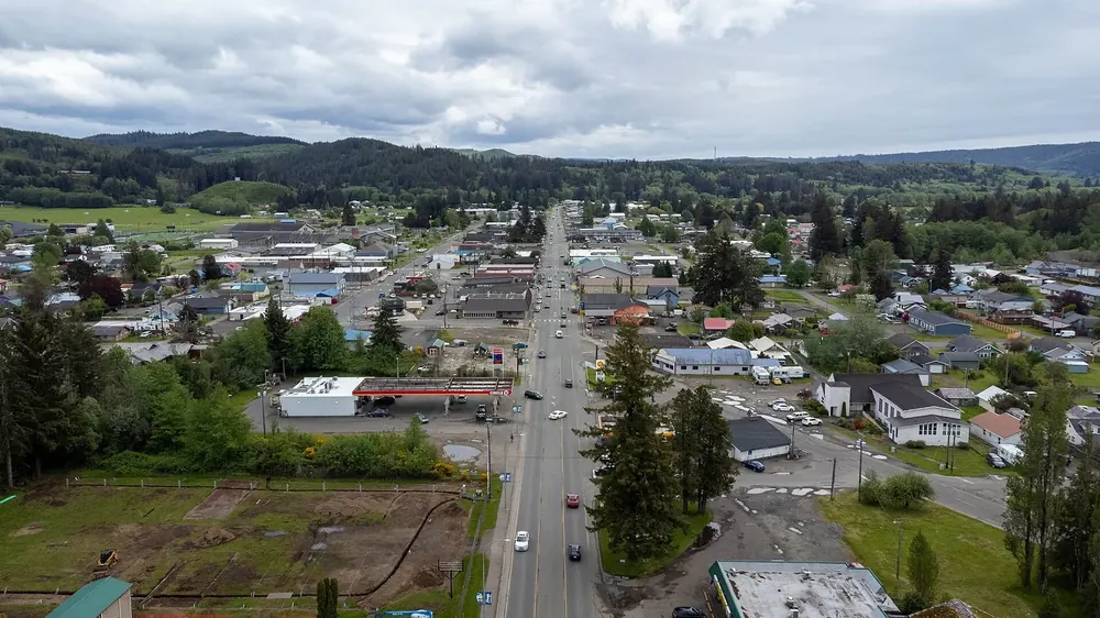 Aerial view of downtown Forks: the main street with shops and houses, surrounded by forest and hills