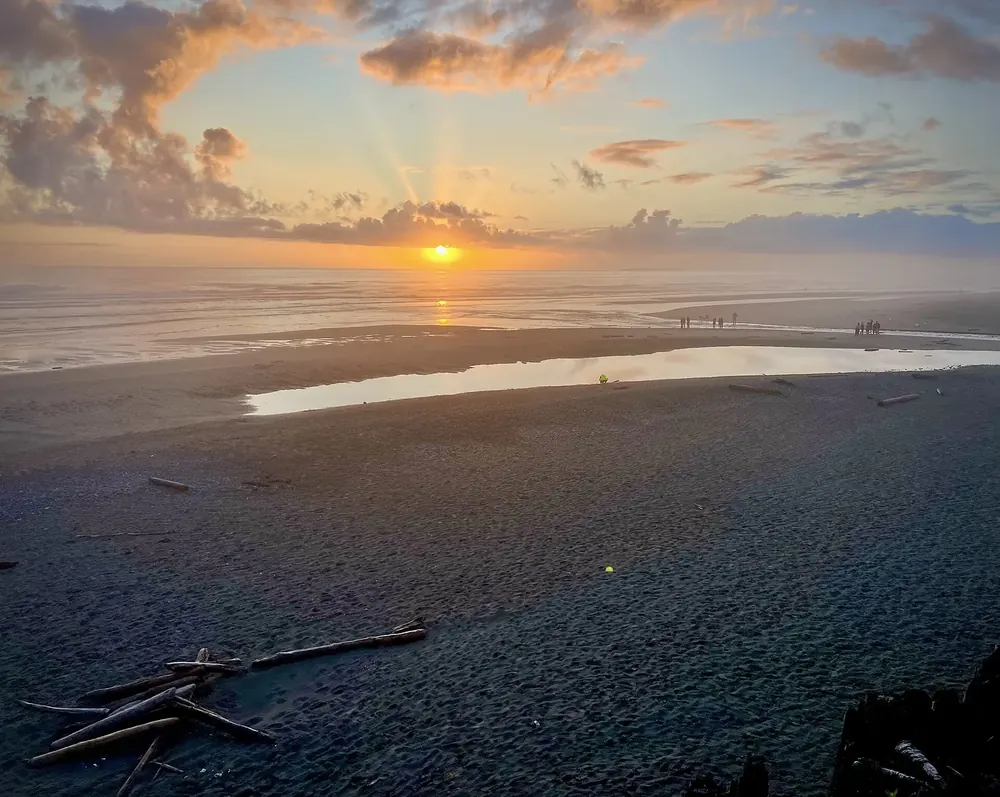 Sunset on the beach at Kalaloch Lodge: sunbeams over the Pacific, wet sand and driftwood in the foreground