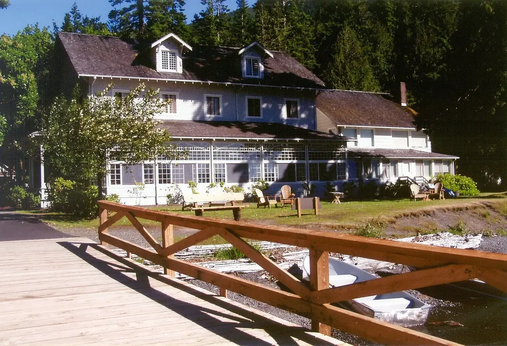 Lake Crescent Lodge from the jetty: a white wooden building with a glazed veranda, wooden railing and lawn in front