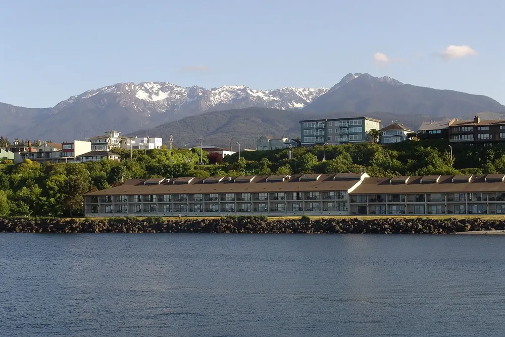 Port Angeles from the harbour: a waterfront hotel and houses on the hillside in front of the snow-capped Olympic Mountains