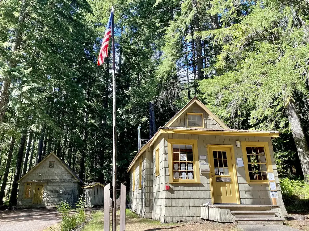 Staircase Ranger Station in Olympic National Park: a small wooden building with yellow windows and a flagpole under tall conifers