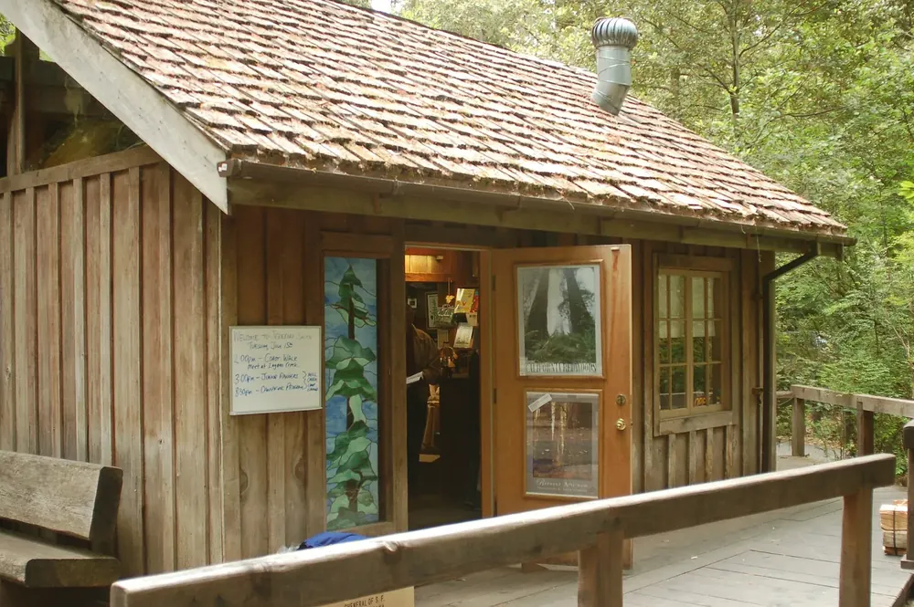 Small wooden visitor centre in Jedediah Smith Campground with a shingle roof, porch and open door
