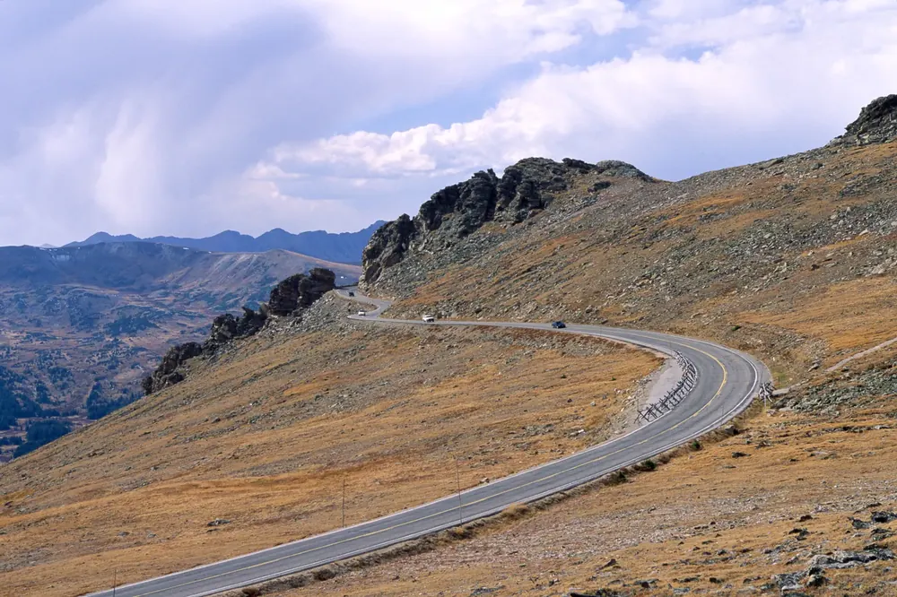 Rock Cut on Trail Ridge Road in Rocky Mountain National Park: a bend in the road through alpine tundra, rock towers beside it and a view of mountain ranges