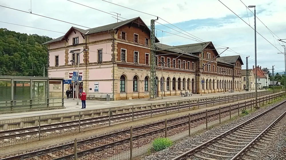 Bad Schandau national park station: a long historic station building behind platforms and tracks under overhead lines