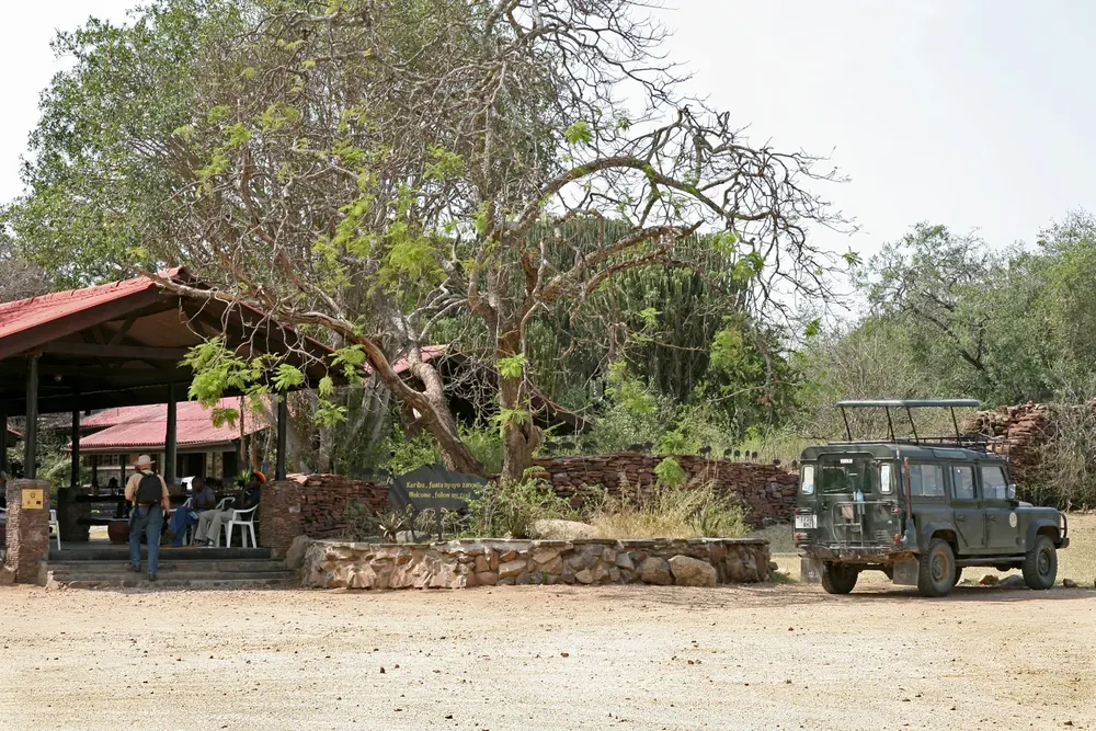 Serengeti National Park Visitor Centre near Seronera: open pavilions under trees, stone walls and a safari vehicle