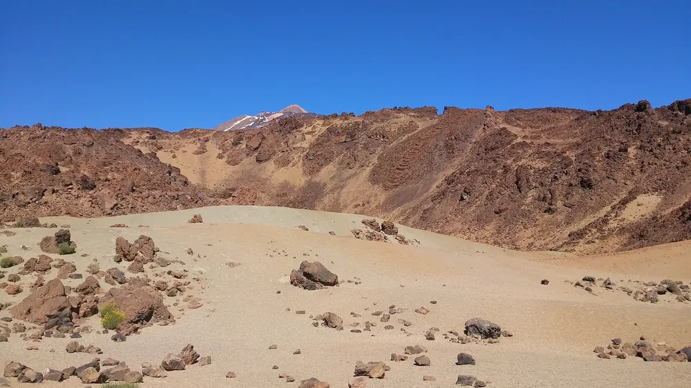 Minas de San José in Teide National Park: pale pumice fields with scattered lava rocks in front of reddish-brown slopes