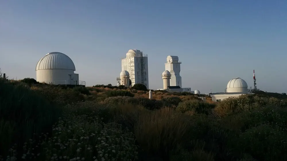 Observatorio del Teide in Teide National Park: white telescope domes and solar towers above broom bushes in the evening light