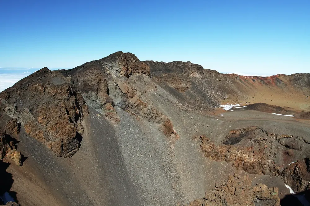 Crater of Pico Viejo in Teide National Park: steep crater walls banded brown and red, with scree slopes and remnants of snow