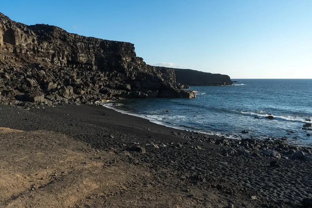 Playa del Paso: dark shingle beach below rugged lava cliffs on the deep blue Atlantic