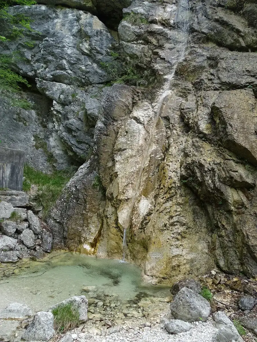 Slap pod Kukljo waterfall in the Juliana Alpine Botanical Garden in Triglav National Park: a thin trickle over a grey rock face into a small pool