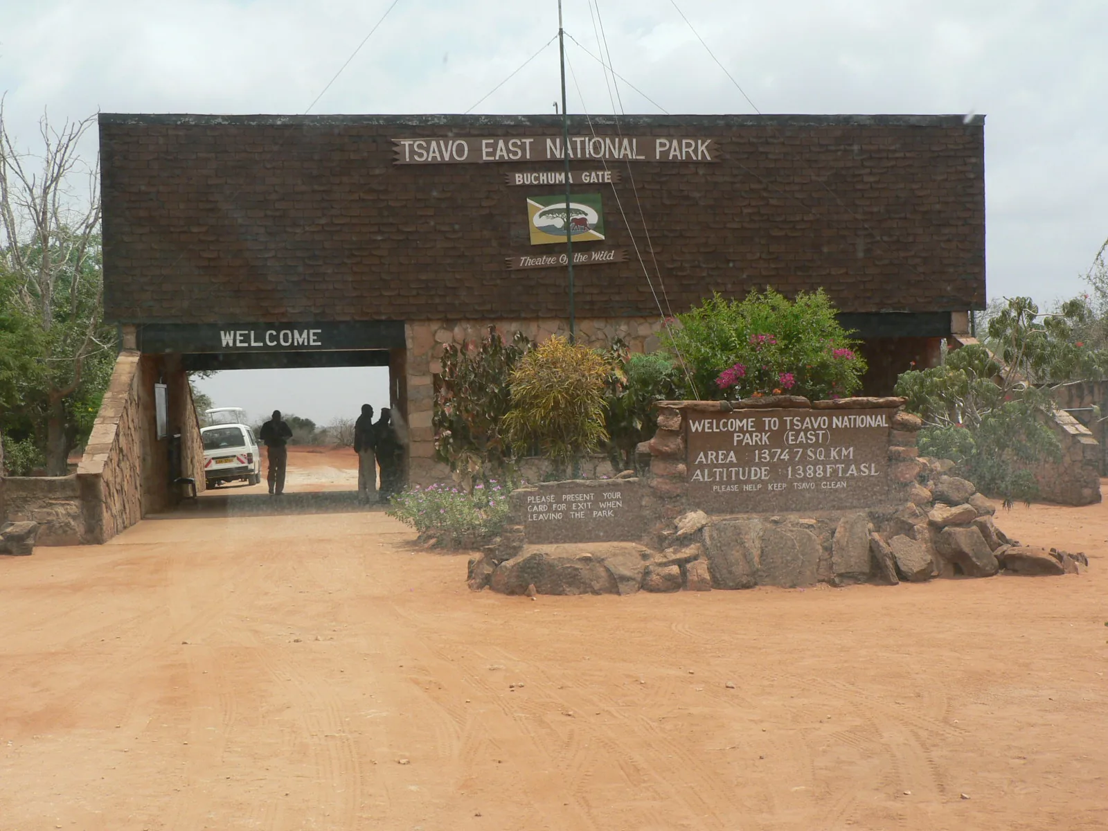 Bachuma Gate of Tsavo East with its gateway arch, welcome sign and stone wall on red soil