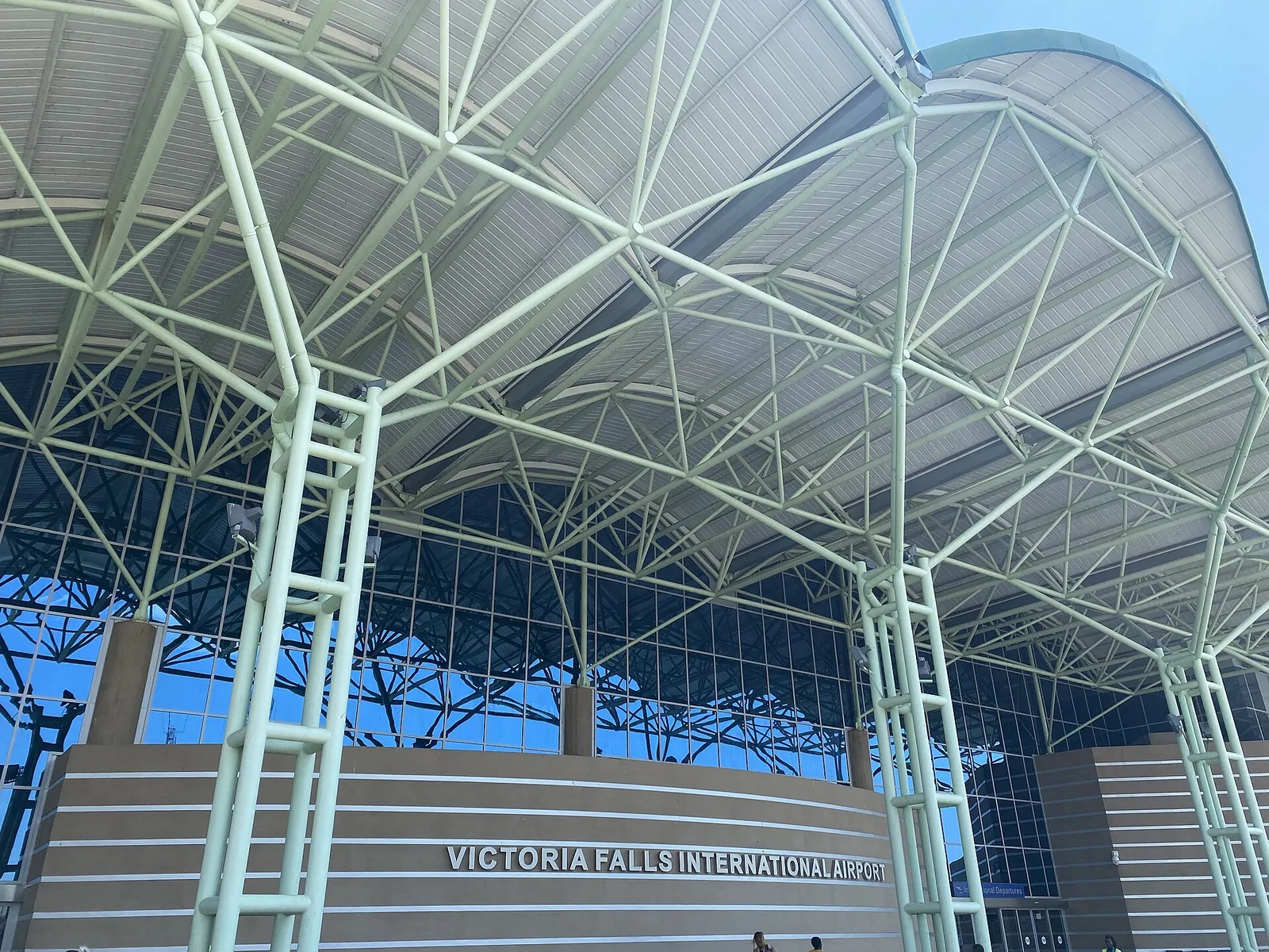 Steel canopy at the entrance of Victoria Falls International Airport with the lettering on the terminal