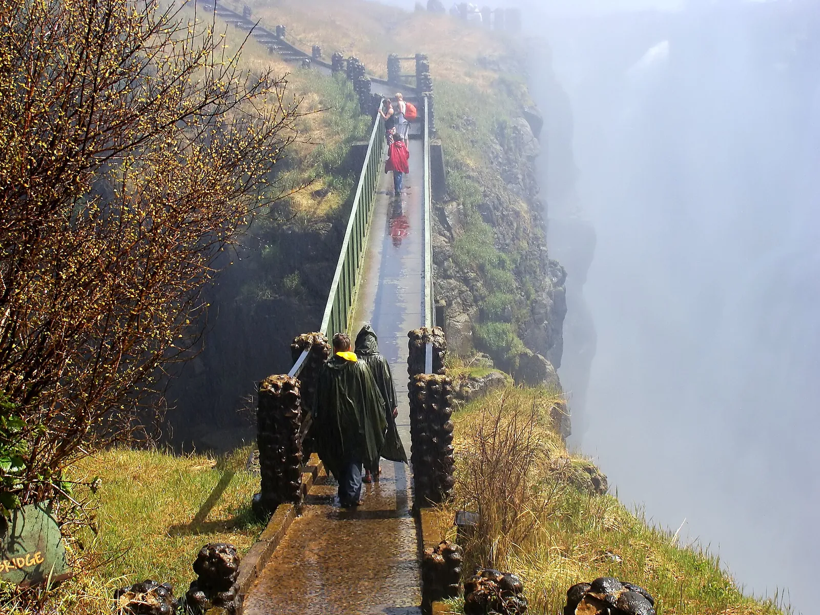 Knife Edge Bridge on the Zambian side of Victoria Falls: a narrow footbridge in drifting spray, visitors in rain ponchos