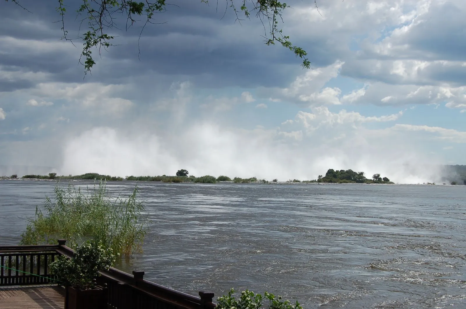 View from the deck of the Royal Livingstone Hotel across the wide Zambezi to the spray cloud of Victoria Falls