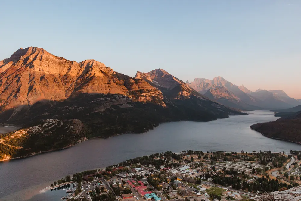 View from Bear's Hump in Waterton Lakes National Park of Waterton townsite and Upper Waterton Lake, mountains behind in warm low-angled light