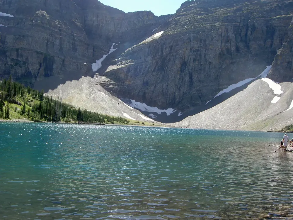 Crypt Lake in Waterton Lakes National Park: turquoise mountain lake in a rocky basin with scree slopes, patches of snow and steep walls