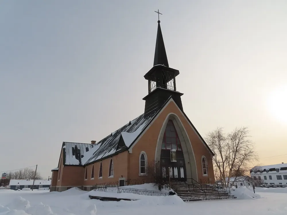 St. Joseph’s Cathedral in Fort Smith in winter: a brick church with a pointed spire behind a snow-covered forecourt