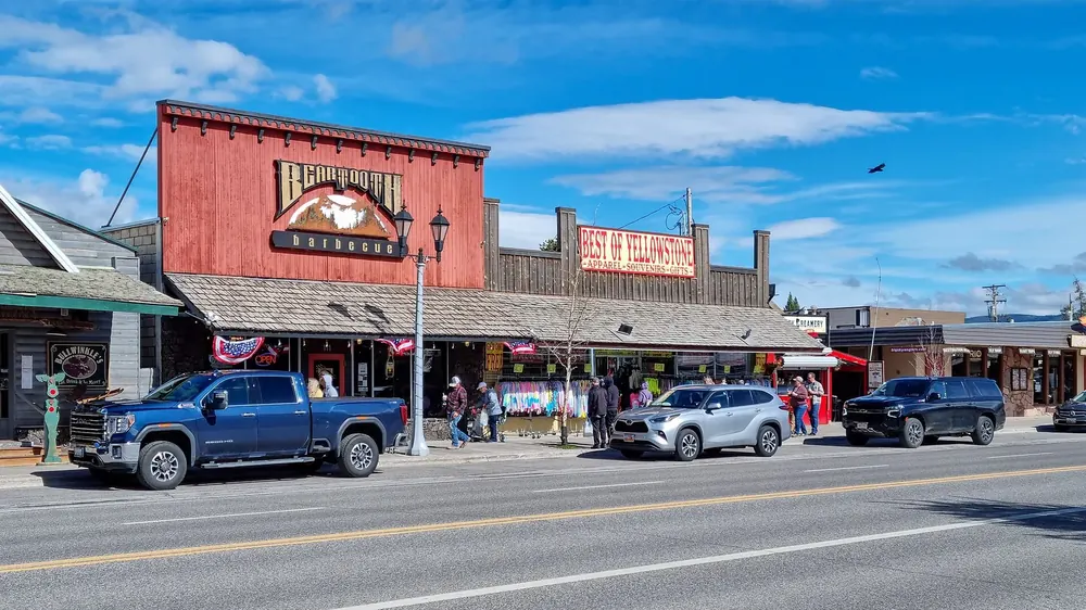Canyon Street in West Yellowstone: shops with Western facades, pickup trucks in front under a deep blue sky