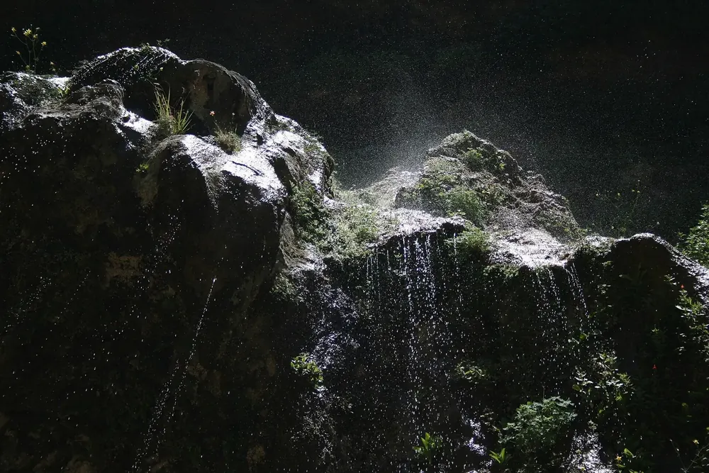 Weeping Rock in Zion National Park: water drips from a mossy, overhanging sandstone cliff against the light.