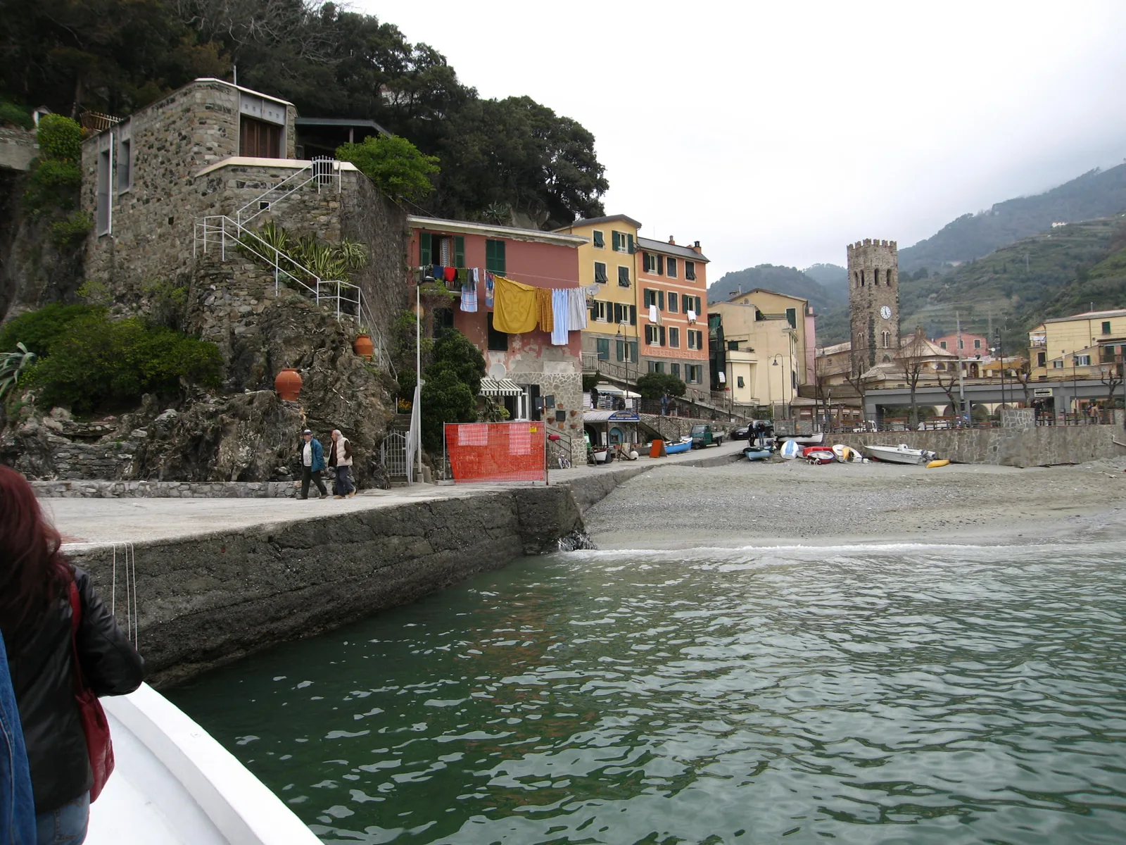 On the old-town beach of Monterosso al Mare: colourful houses, a tower and boats on the shingle