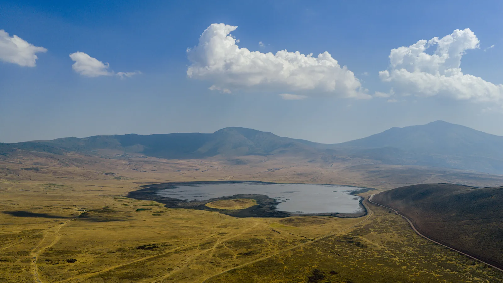 The Ngorongoro Crater from the air: the pale Lake Magadi on the floor, the crater walls all around under clouds
