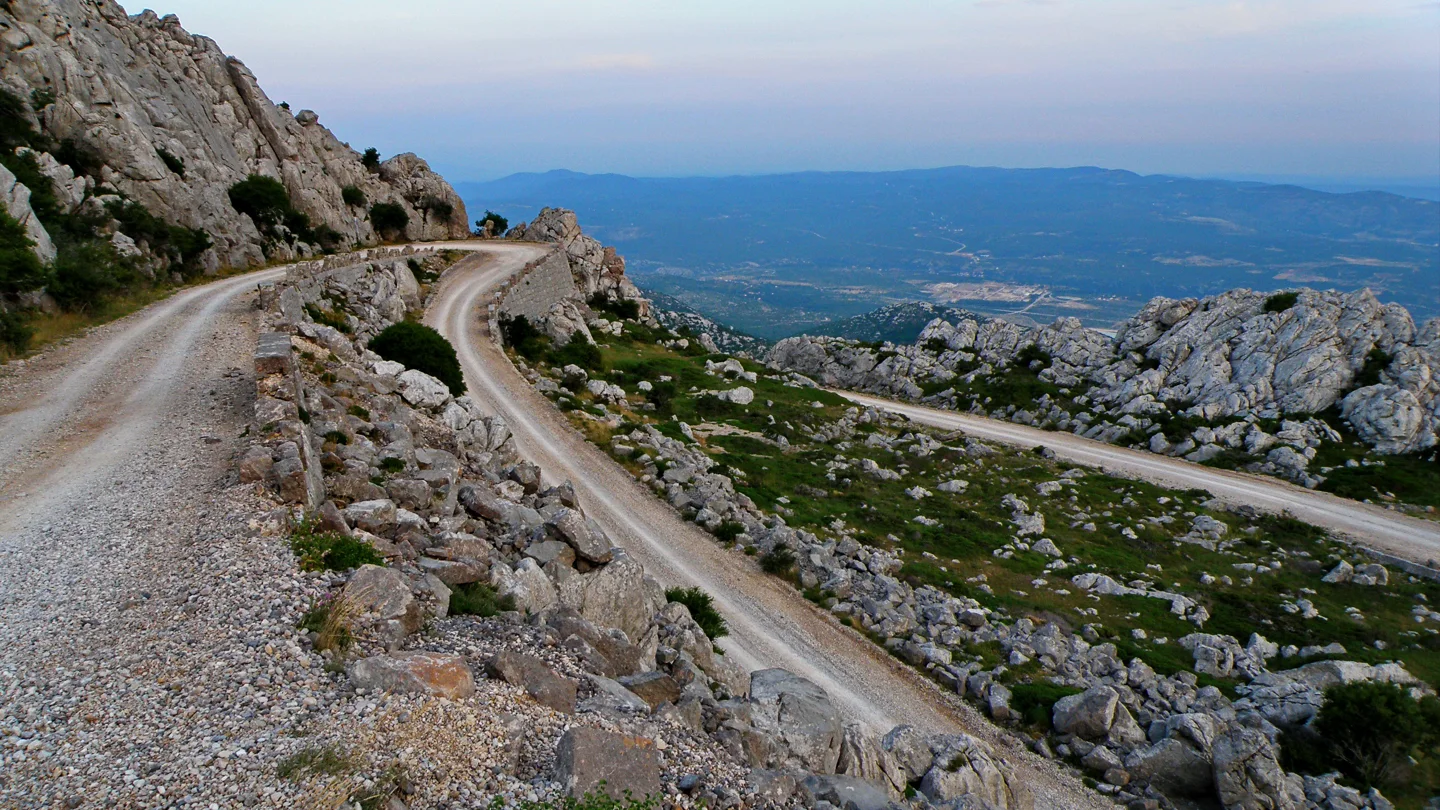 Gravel road between karst rocks in Northern Velebit National Park, with a wide view inland