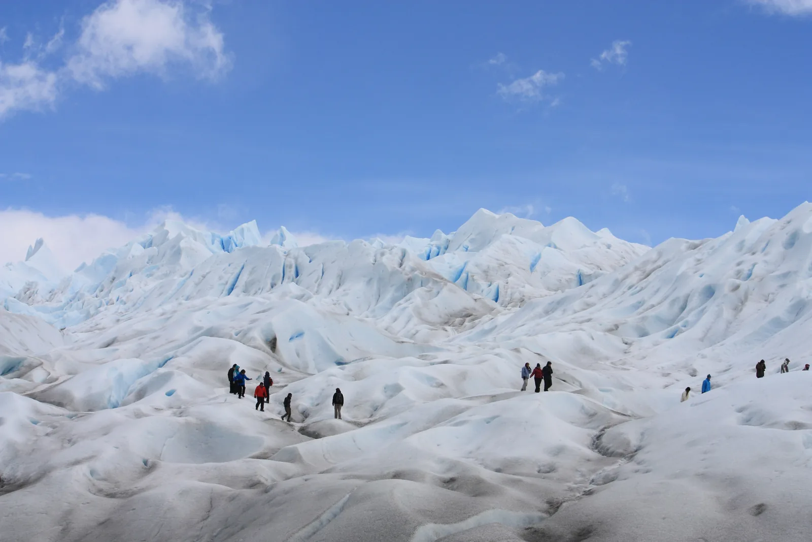 Hikers in crampons on the ice of the Perito Moreno Glacier in Los Glaciares National Park, among white ice mounds