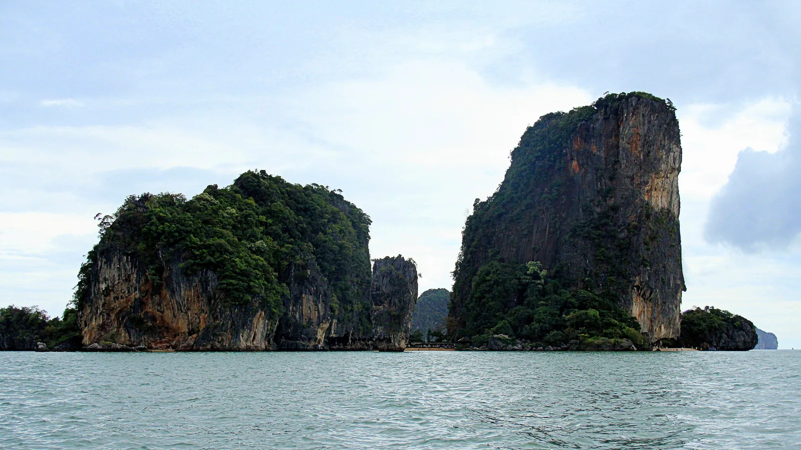 The overgrown limestone rocks of Khao Phing Kan in Ao Phang Nga National Park, the tall rock tower to their right, seen from the water