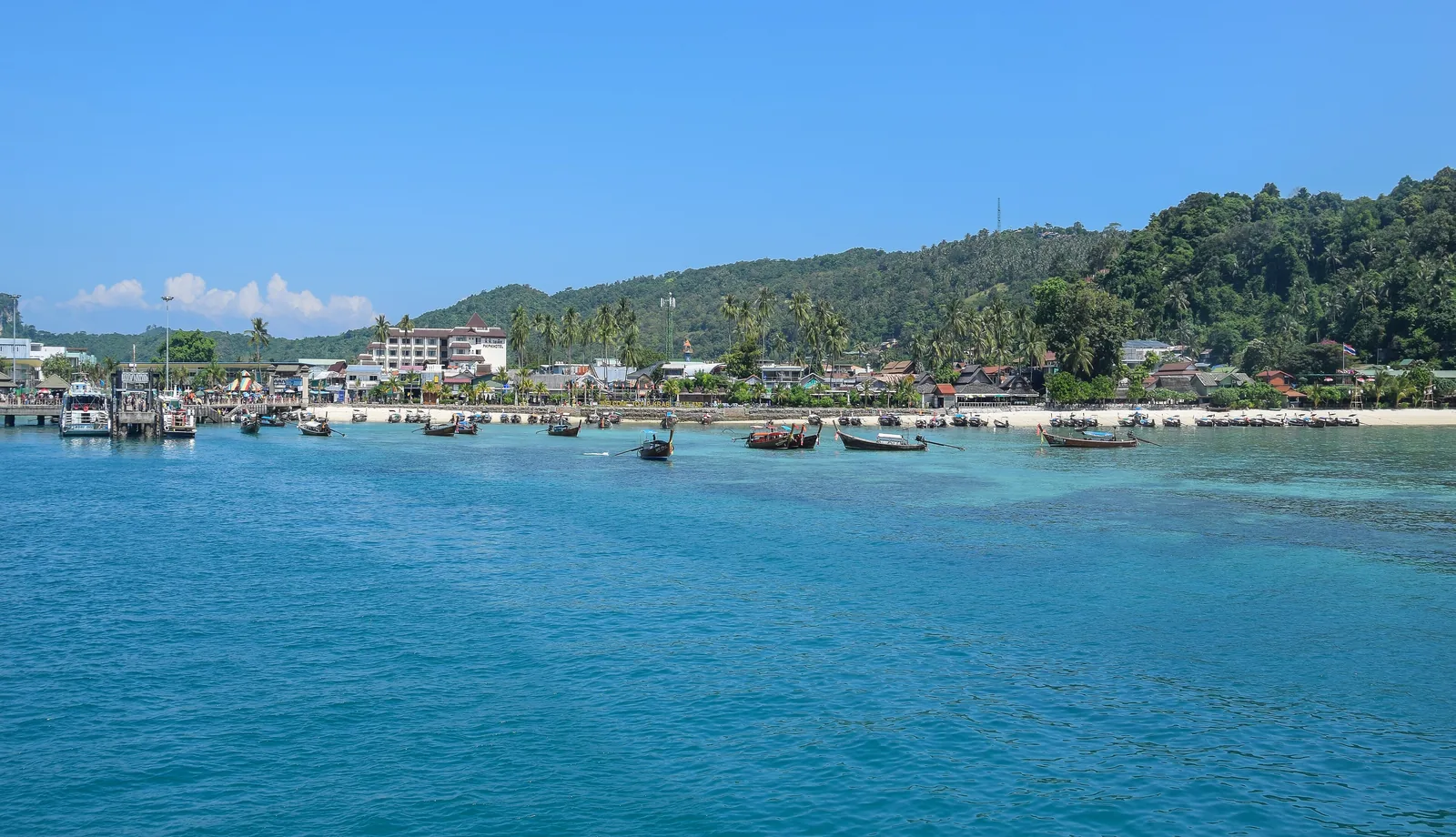 Ton Sai Bay on Ko Phi Phi Don with boats offshore, houses along the beach and forested hills behind