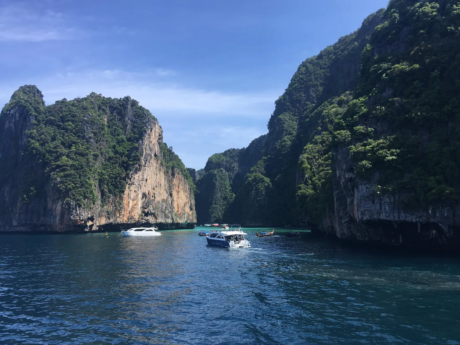 Two speedboats entering Pileh Lagoon in Phi Phi National Park between tall, overgrown limestone cliffs