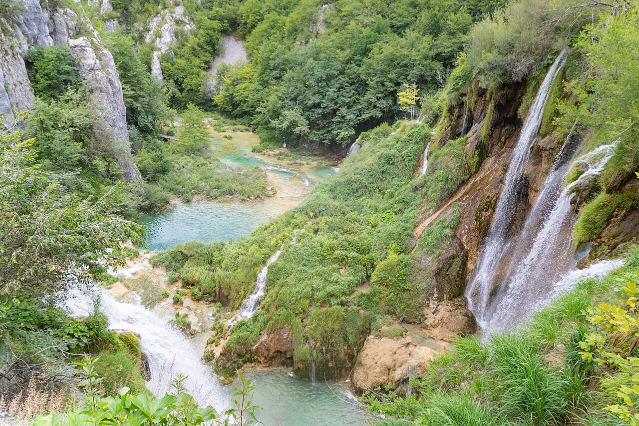 Veliki Slap waterfall beside the turquoise Lower Lakes in Plitvice Lakes National Park, falling over a green rock face