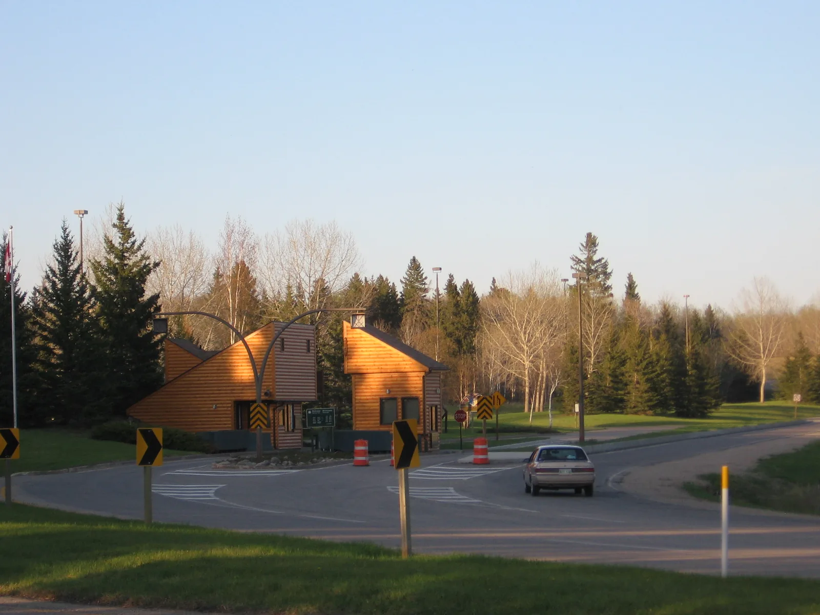 The wooden park gate building on Highway 10 near Wasagaming, with the road and a passing car in front