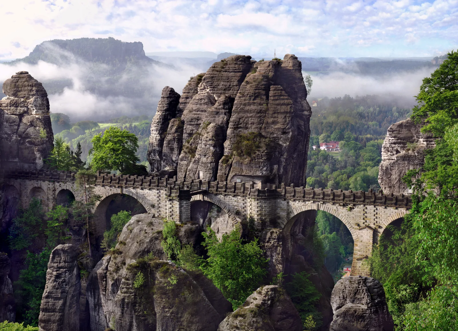 The Bastei Bridge in Saxon Switzerland National Park spans the gap between sandstone towers, with the Lilienstein above the Elbe valley behind
