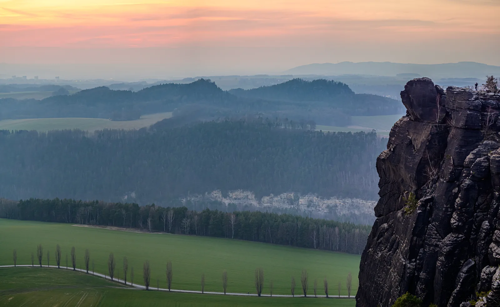 View from the Lilienstein in Saxon Switzerland National Park at sunrise over layered ridges and banks of fog