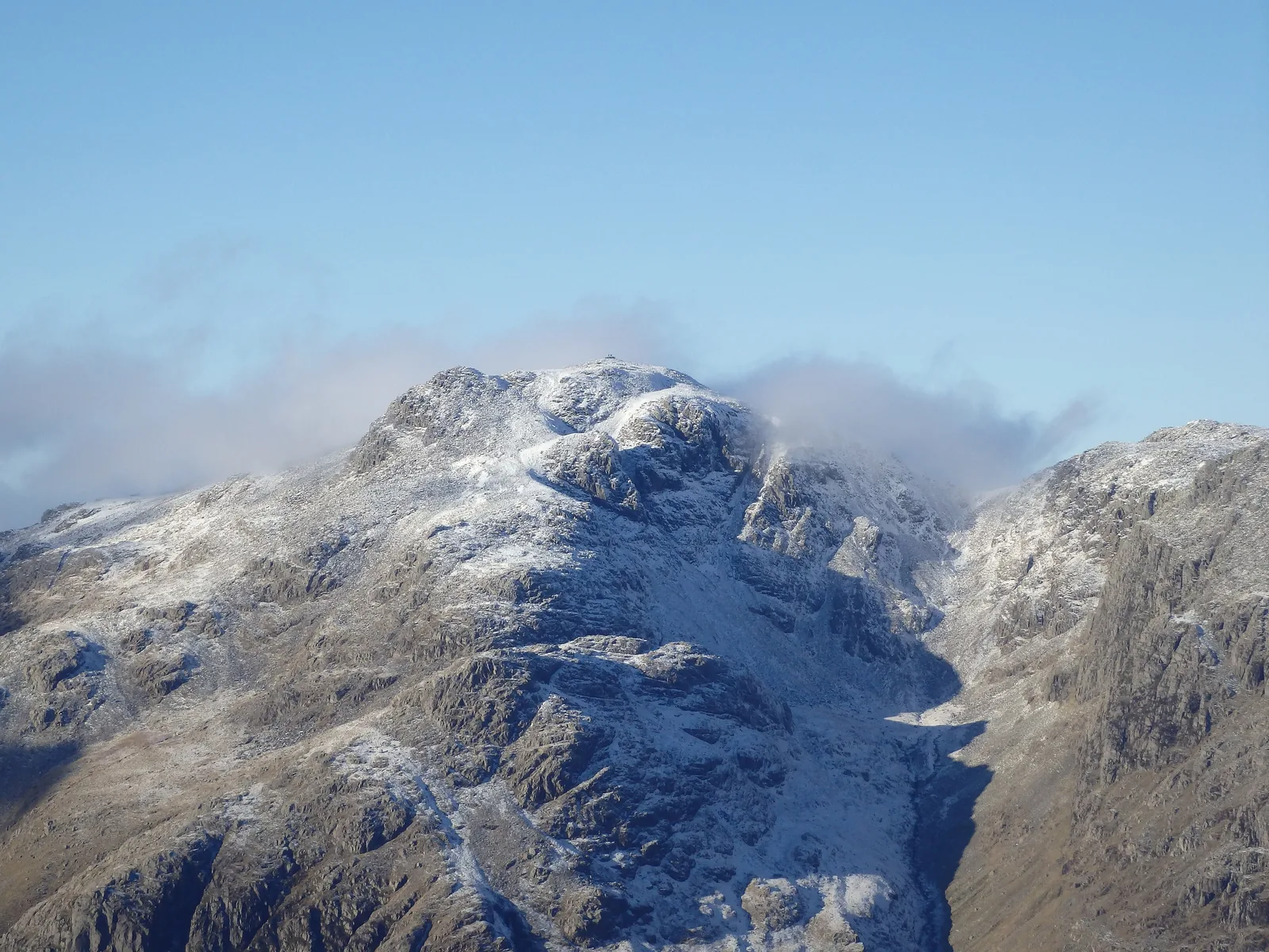 Snow-covered Scafell Pike in the Lake District National Park under clouds, seen from Crinkle Crags