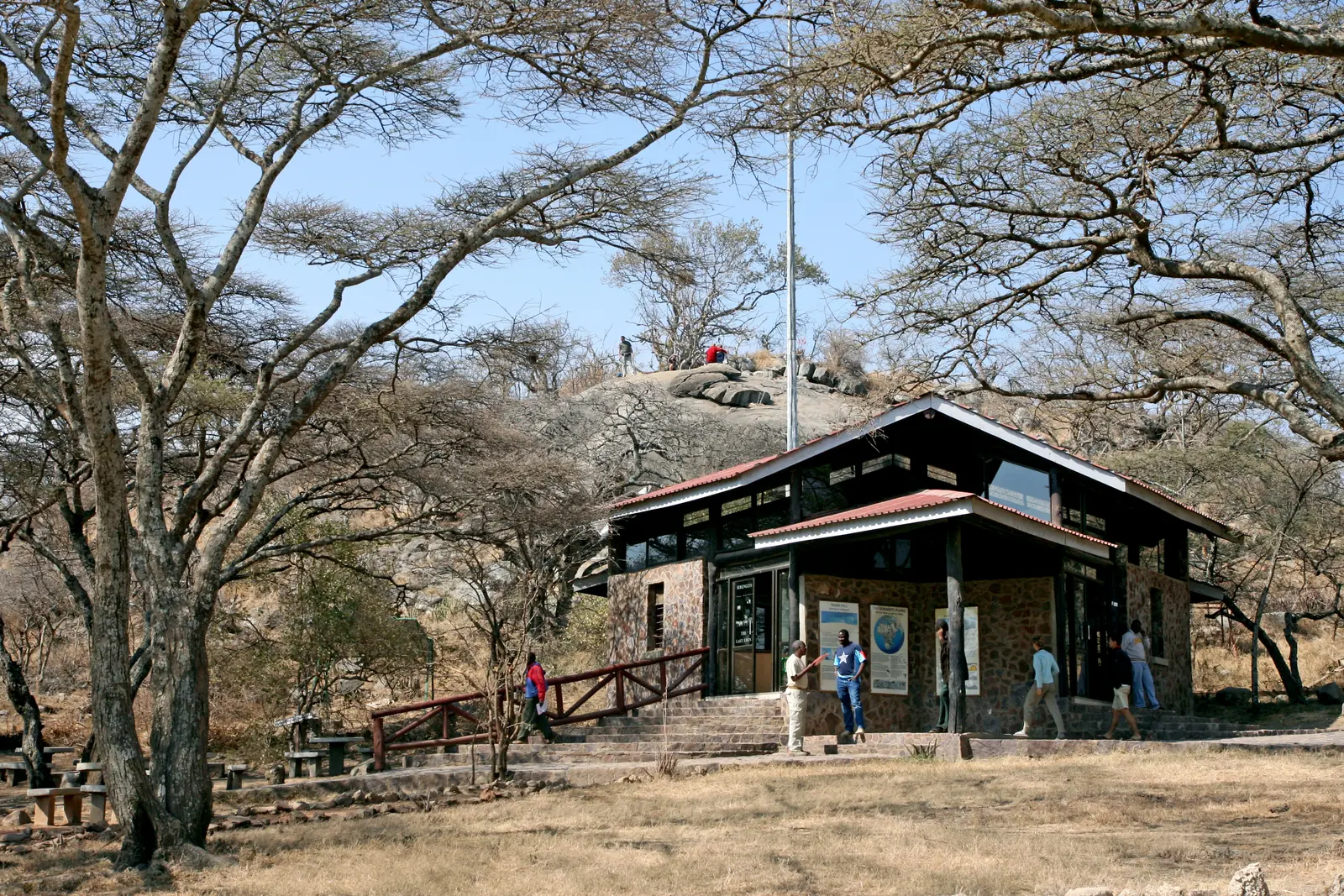 The gate building at Naabi Hill in Serengeti National Park under acacias, visitors at the ramp