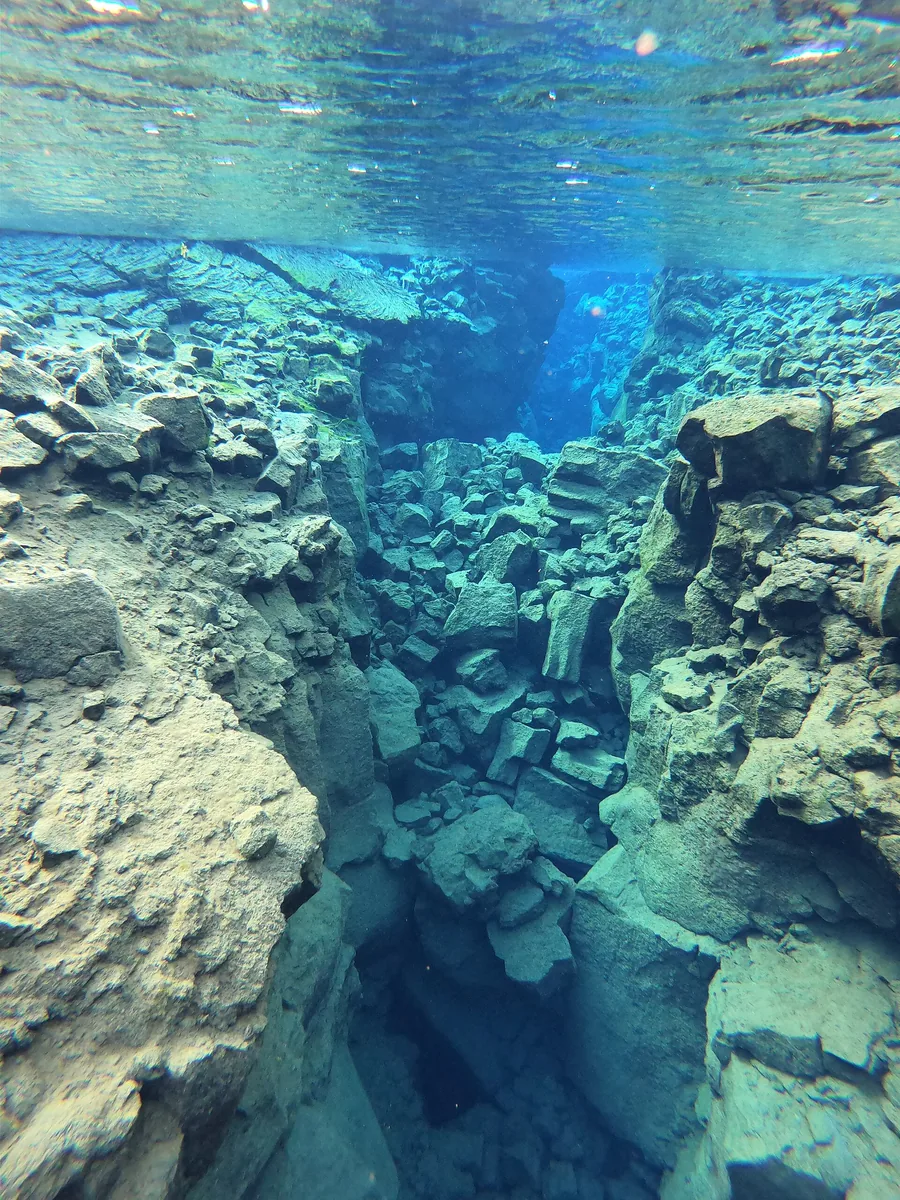 Underwater view into the Silfra fissure: turquoise, clear water between pale lava walls