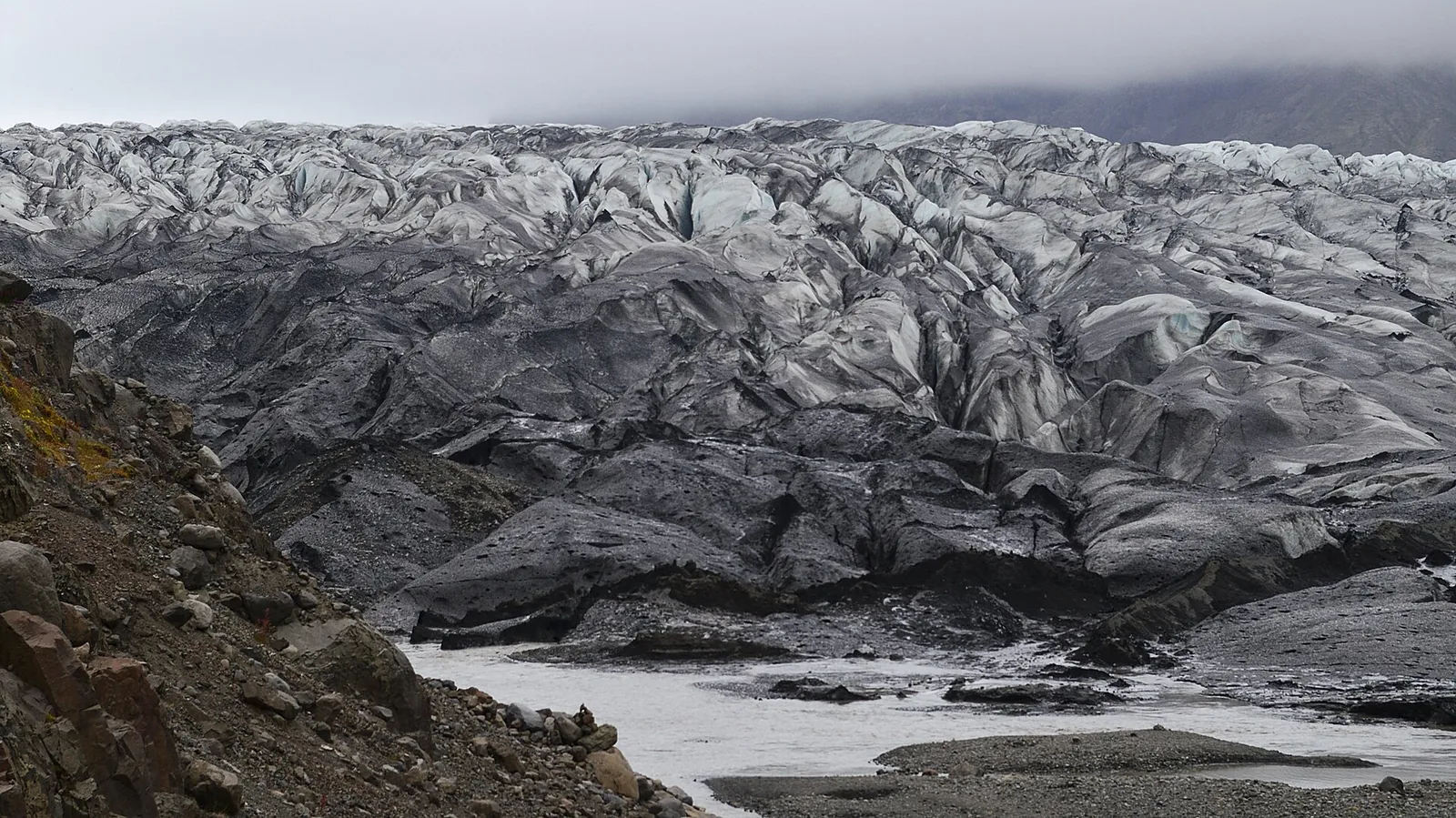 The crevassed snout of Skaftafellsjökull in Skaftafell, moraine debris and meltwater in front
