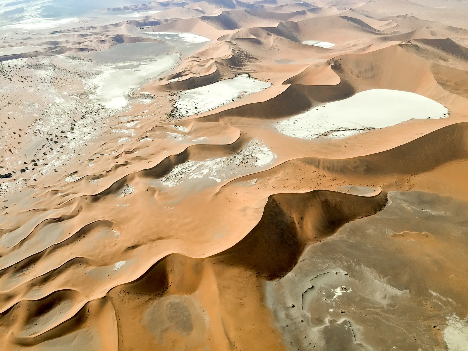 Aerial view of Sossusvlei in Namib-Naukluft National Park: pale clay pans between red star dunes
