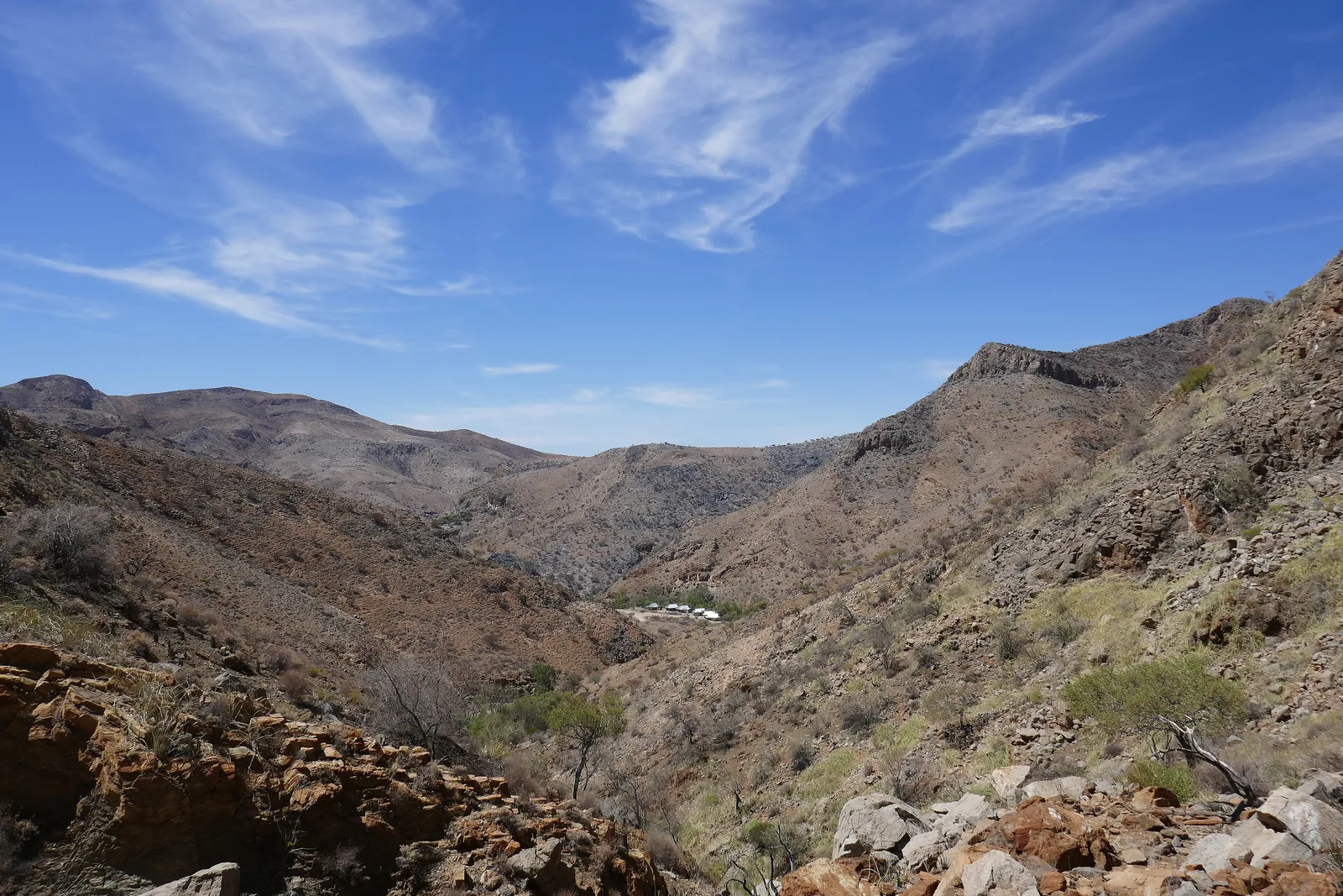 Rocky ridges and a valley with acacias in the Naukluft Mountains in Namibia under a blue sky