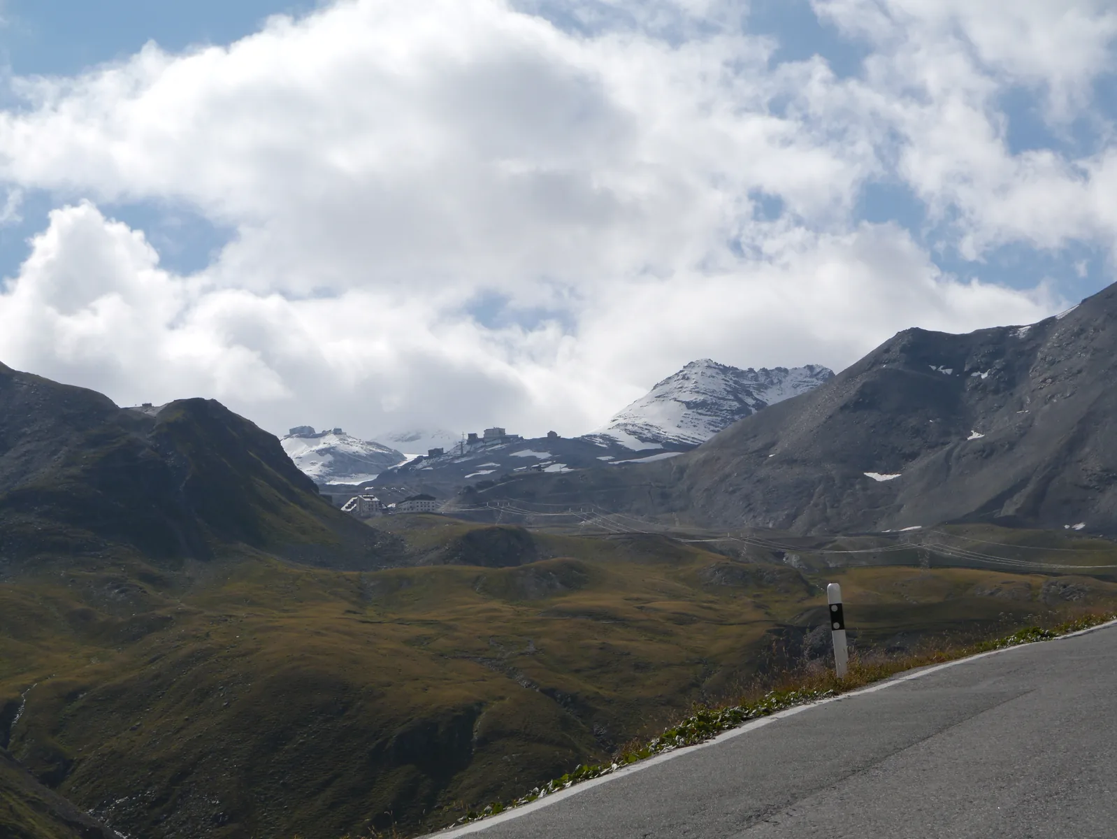 View from the Umbrail Pass of the road to the Stelvio Pass, with snow-patched peaks behind