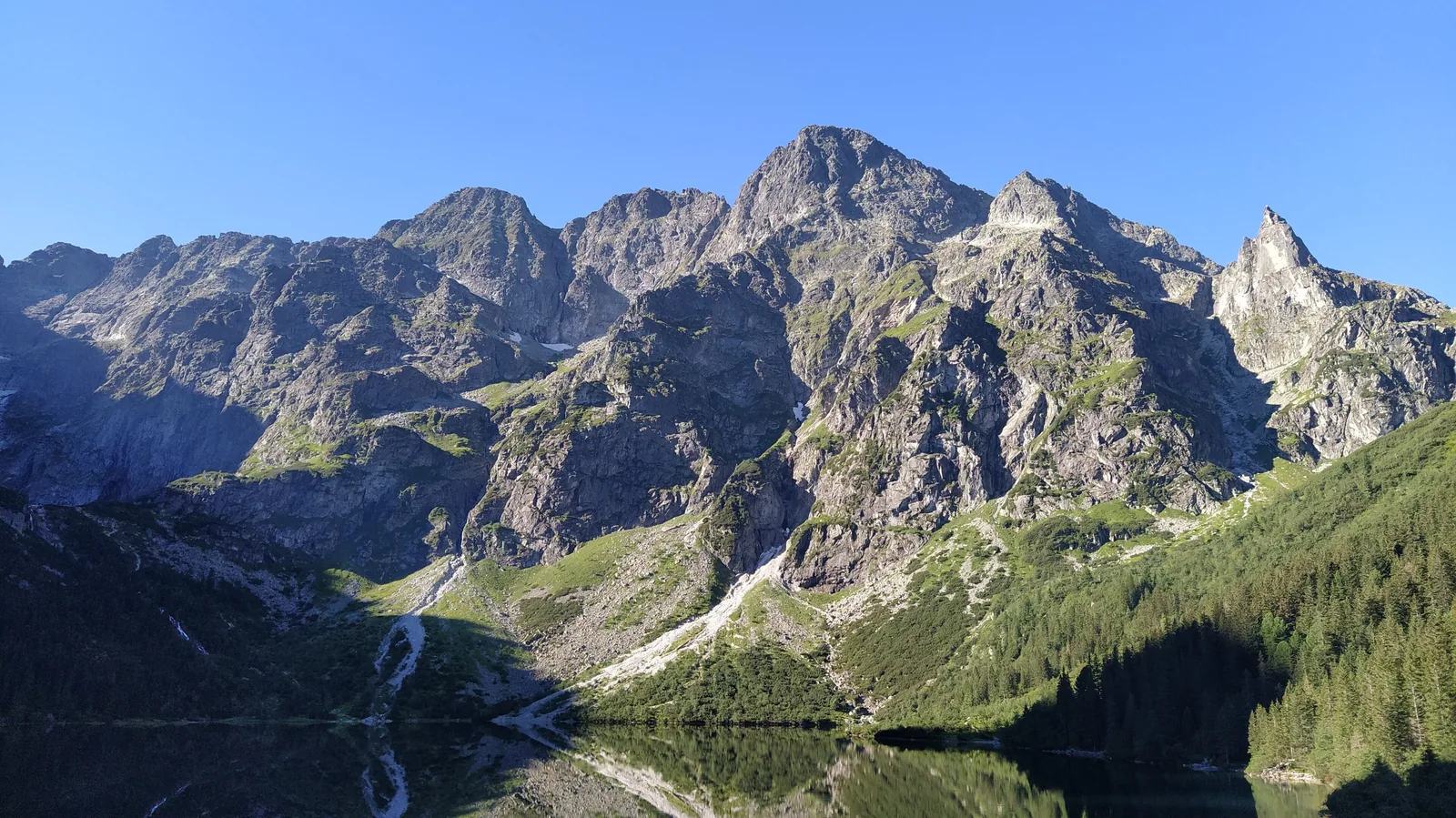 View across Morskie Oko in Tatra National Park to the rock walls of the High Tatras under a clear sky