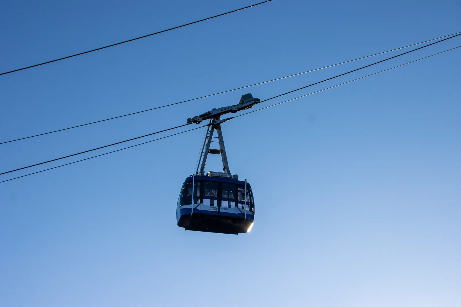 A Teide cable car cabin in Teide National Park hanging from its cable against a blue sky