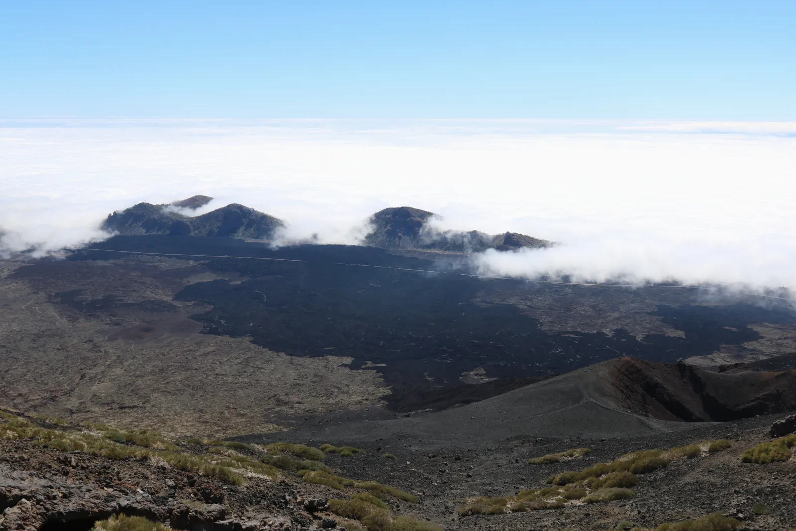 Clouds spilling over the rim of the caldera in Teide National Park, with dark lava fields on the slope of Pico Viejo in front