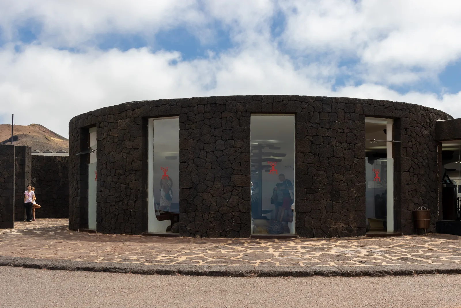 The round building of black lava stone in Timanfaya National Park on Islote de Hilario, with its glass front and visitors outside