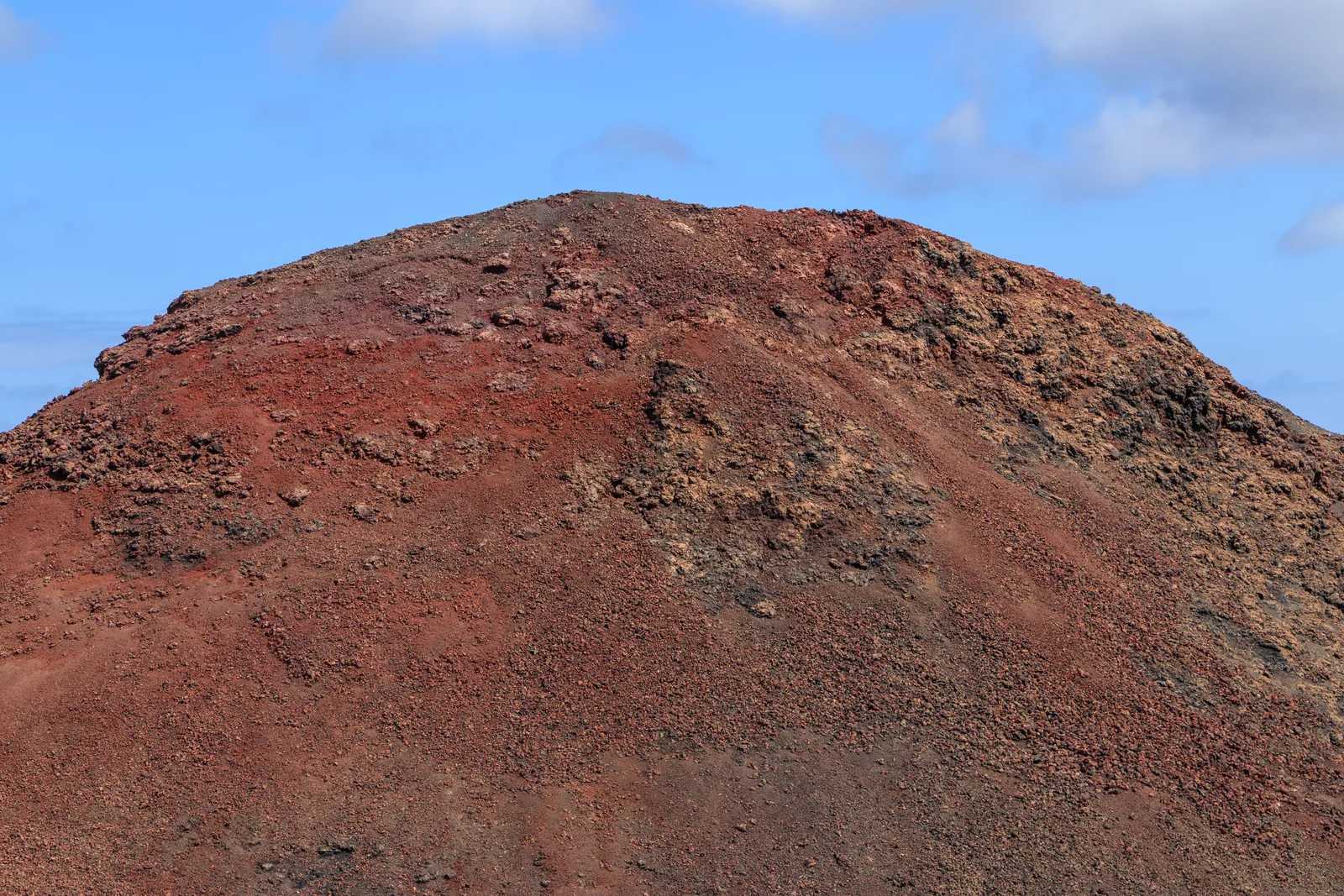 The red ash cone of Montaña del Balcón in Timanfaya National Park under a blue sky
