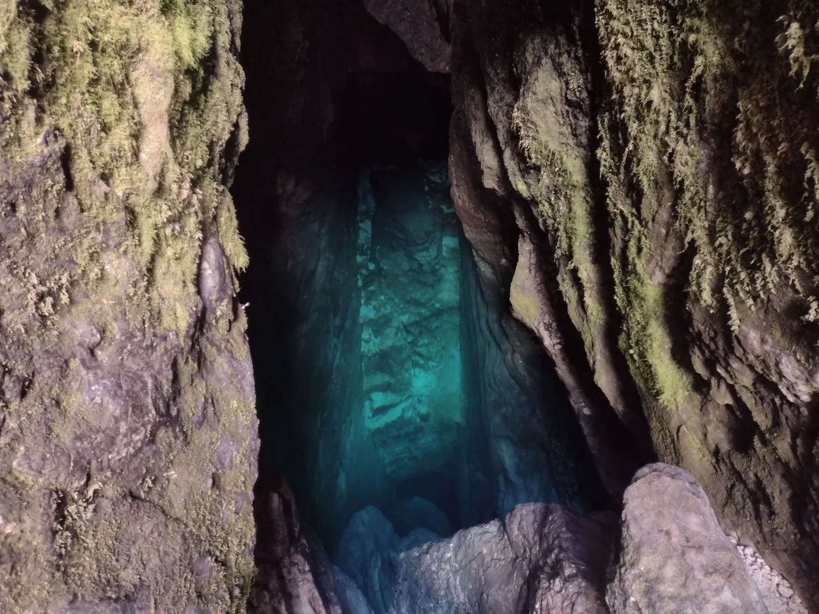 View into the cave of the Soča source in Triglav National Park, with deep, blue-green water