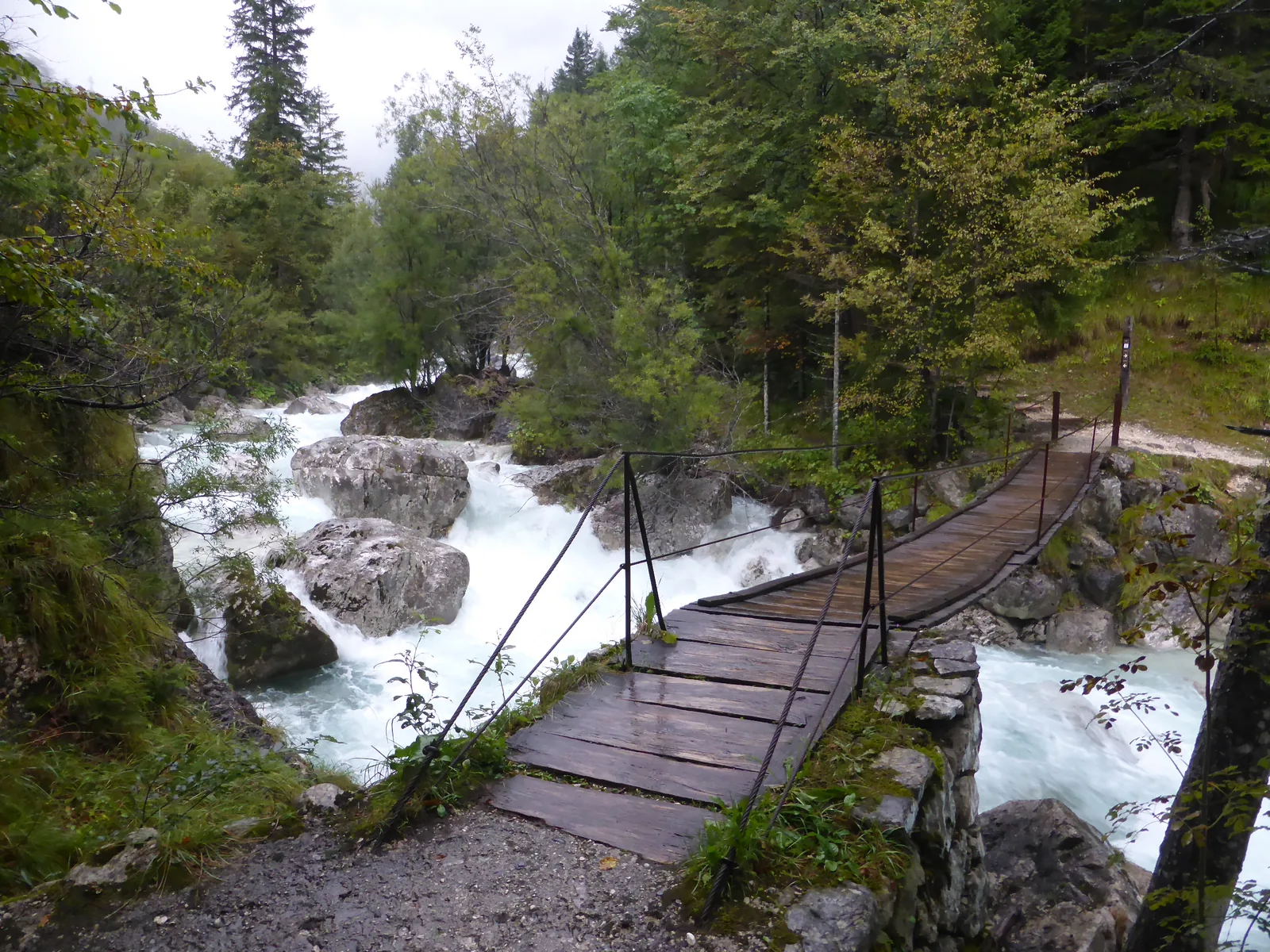 A wooden footbridge crosses foaming water on the Soča Trail in Triglav National Park