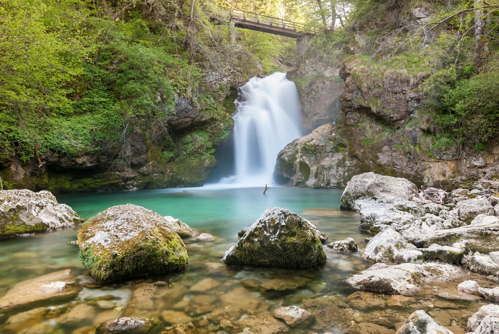 The Šum waterfall at the end of Vintgar Gorge in Triglav National Park, with a clear turquoise pool in front
